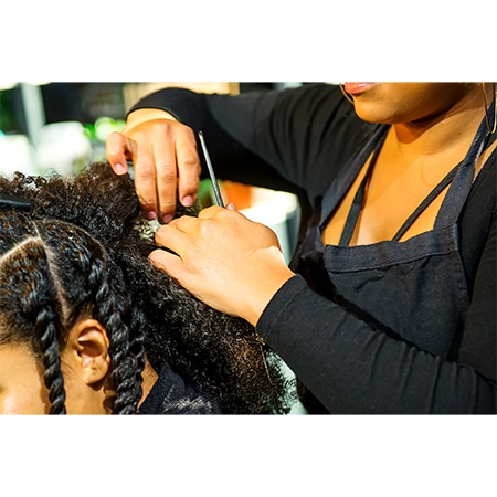 Beautiful black woman at salon getter her hair retwisited by another sister using special tools.