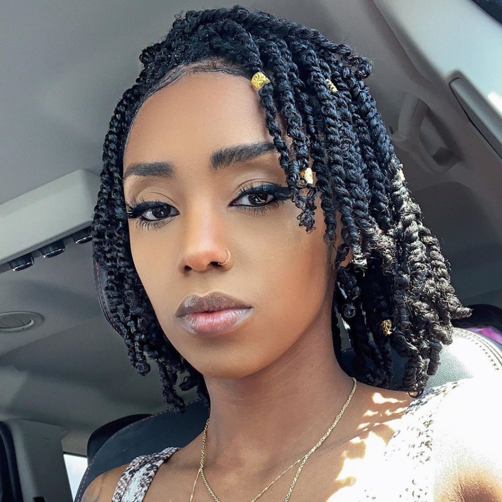 Black model with short black passion twisted crochet hair sitting in a car.