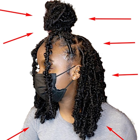 Arrows pointing at a half up half down bun medium crochet faux loc design on a young black model female.